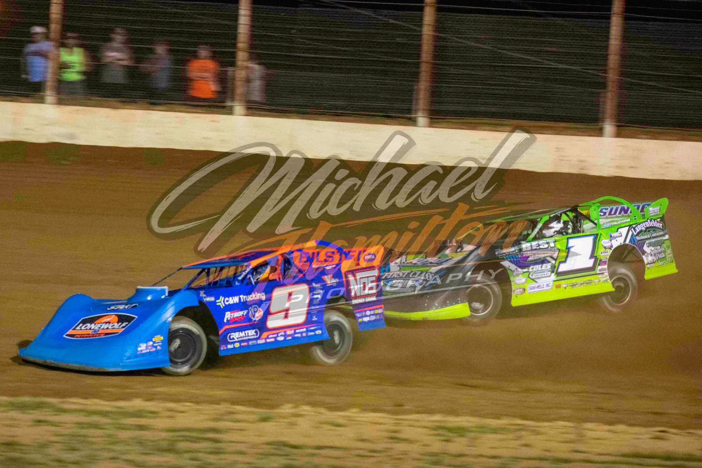 Two dirt late models racing side by side